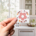 A hand holding a small square object with the text "KNOW YOUR WORTH" and a flower graphic on it.