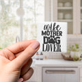 A hand holding a small white object with black text that says "wife mother dog lover".