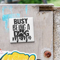 A sticker with the text "BUSY BEING A DOG MAMA" is attached to a concrete surface.