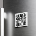 A white square magnet with black text that says "LEAVES AREFALLING AUTUMN IS CALLING" is mounted on a metallic surface.