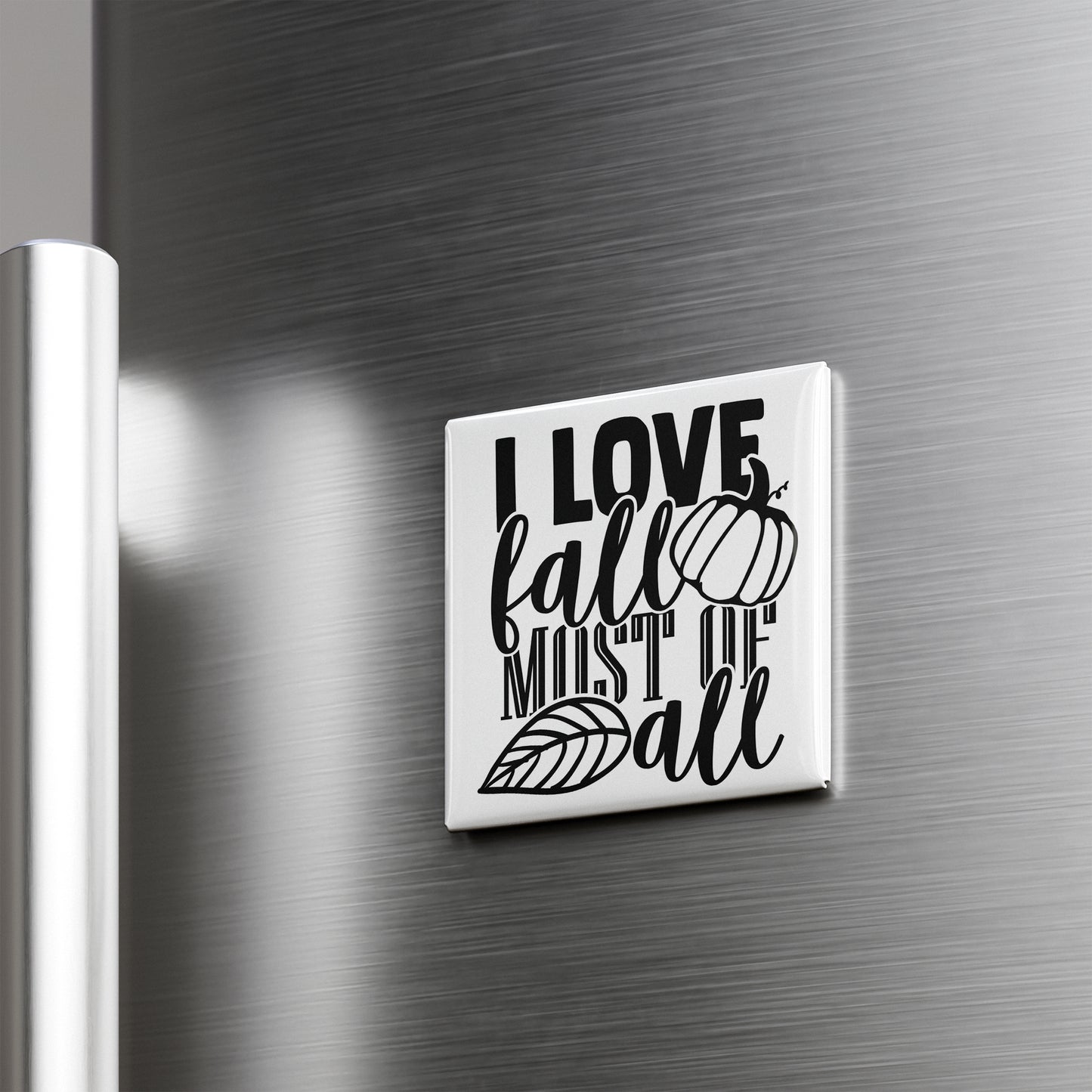 A white square magnet with the text "I LOVE fall MOST of all" printed on it, attached to a metallic surface.