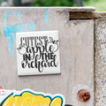 a white square magnet with the text "CUTEST APPLE IN THE ORCHARD" written on it, which is attached to a concrete wall.