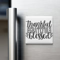 A white refrigerator magnet with the text "Thankful Grateful Blessed" written on it.