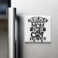 A refrigerator door with a humorous magnet that reads "I'm not like a regular mom, I'm a cool mama" in a playful, tongue-in-cheek font.